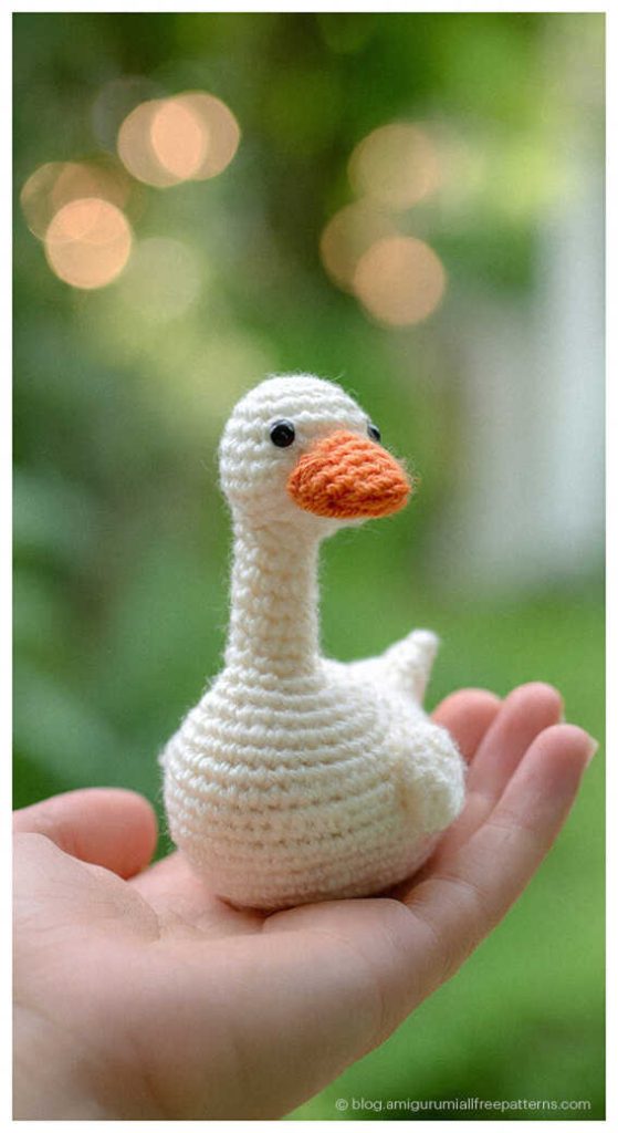 Amigurumi goose crochet toy held in hand with green background, cute crochet goose for handmade decor