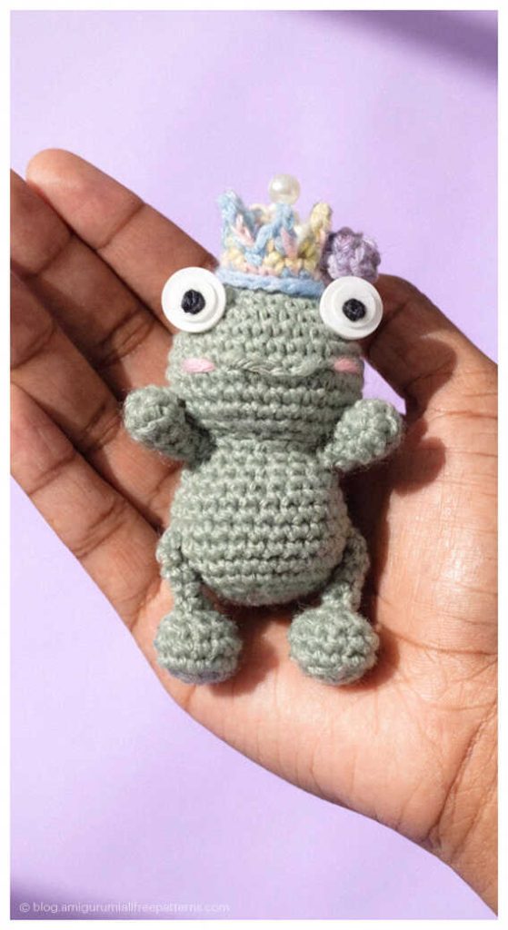 Small gray amigurumi frog with colorful crown held in hand, free beginner-friendly crochet frog pattern