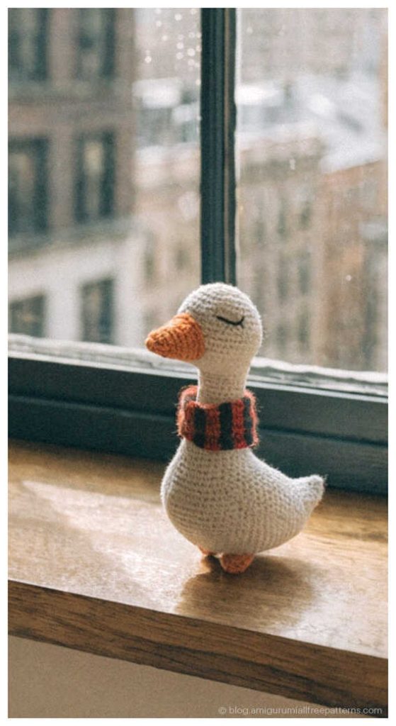 Sleeping amigurumi goose crochet toy by a window with city view, adorable crochet goose gift