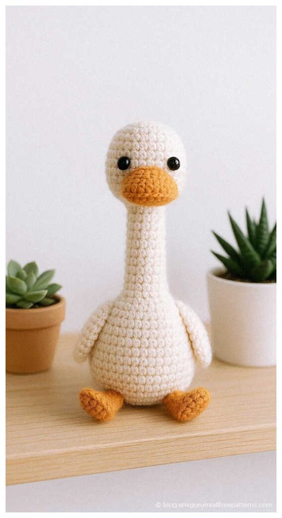 Amigurumi goose crochet toy sitting on a shelf with small plants, cute crochet goose decor