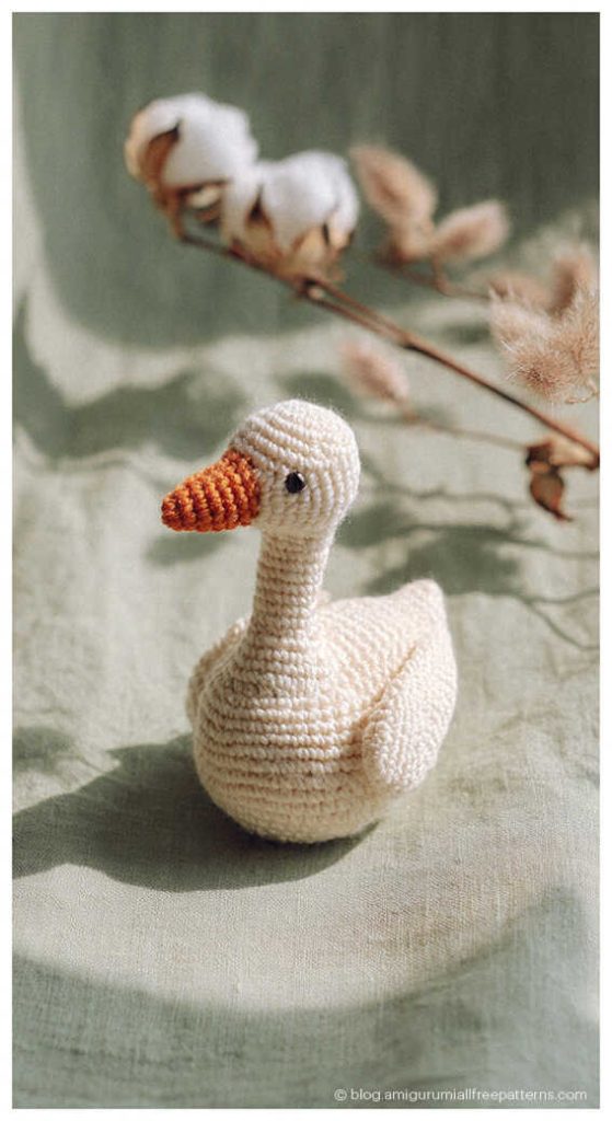 Small amigurumi goose crochet toy on soft fabric with natural light, adorable crochet goose decor