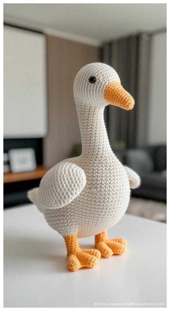 Cute amigurumi goose crochet toy standing on a table indoors, handmade crochet goose plush