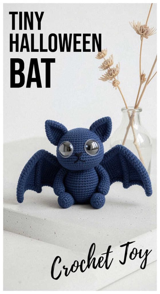 Cute blue amigurumi bat with spread wings sitting on a white surface, crochet bat plush toy