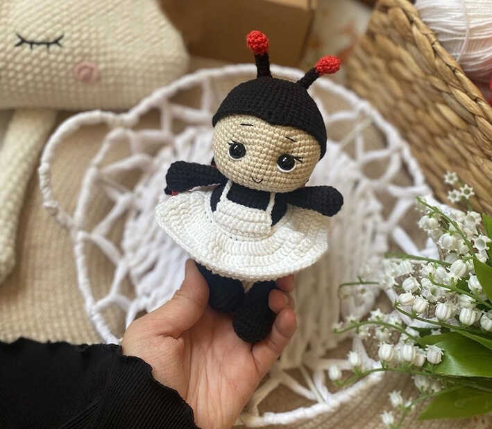 Amigurumi ladybug doll with black and white dress held in hand, free crochet ladybug pattern