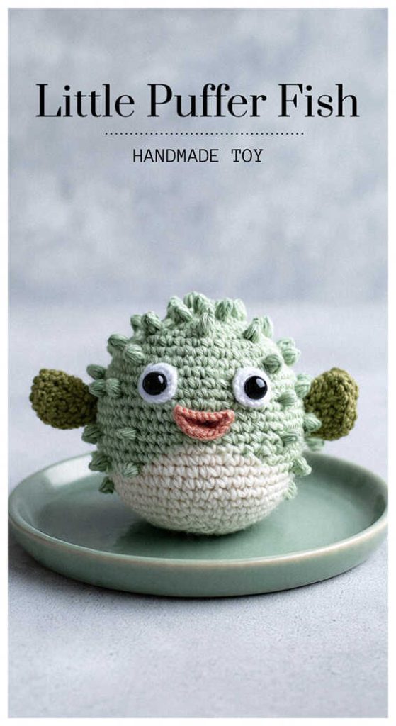 Green little amigurumi puffer fish sitting on a plate, adorable crochet sea animal toy