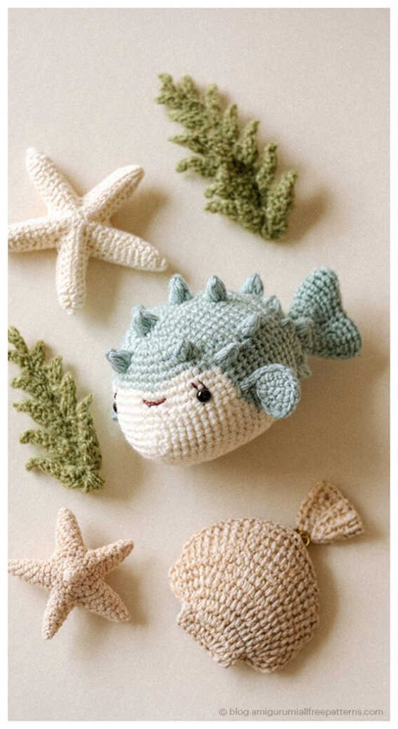 Small green amigurumi puffer fish crochet toy with starfish and seashell decor, cute ocean crochet idea