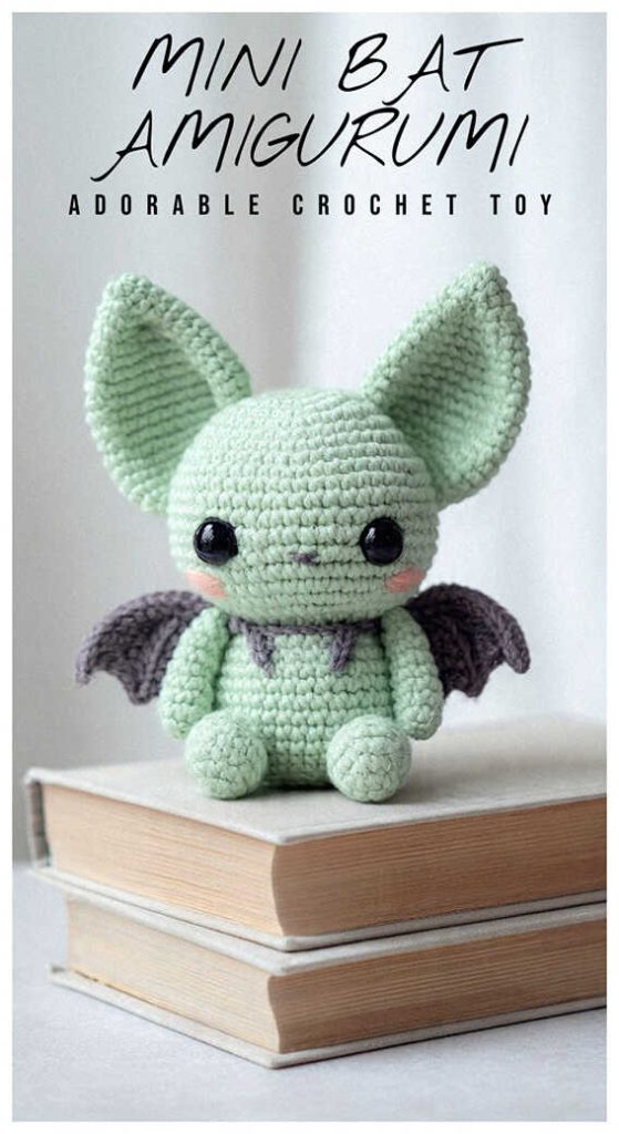 Cute mint green amigurumi bat sitting on stacked books, crochet bat plush toy