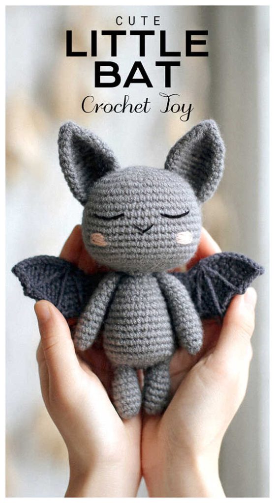 Small gray amigurumi bat with closed eyes held in hands, adorable crochet bat plush toy