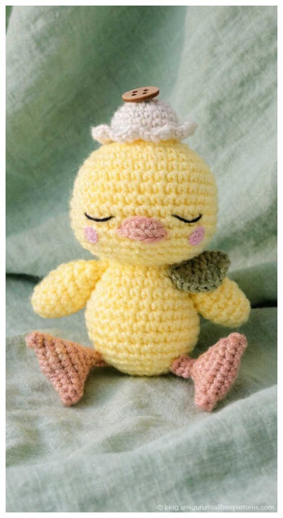 Cute amigurumi chick crochet toy with button hat sitting on fabric, tiny crochet chick plush